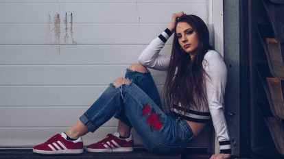 woman in white long sleeve shirt and blue denim jeans sitting on white wooden fence